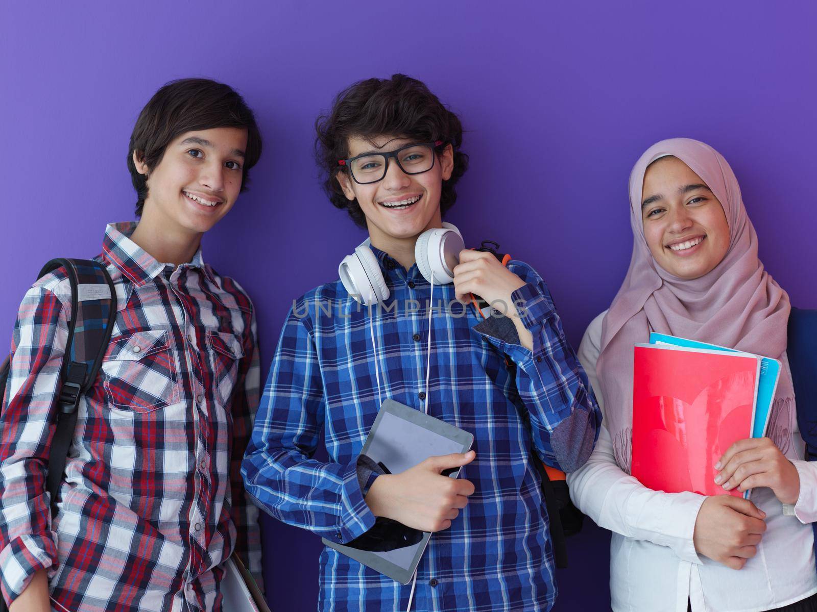 Arabic teenagers as team, students group working together on project using  laptop and tablet computer  online classroom  elearning education concept purple background