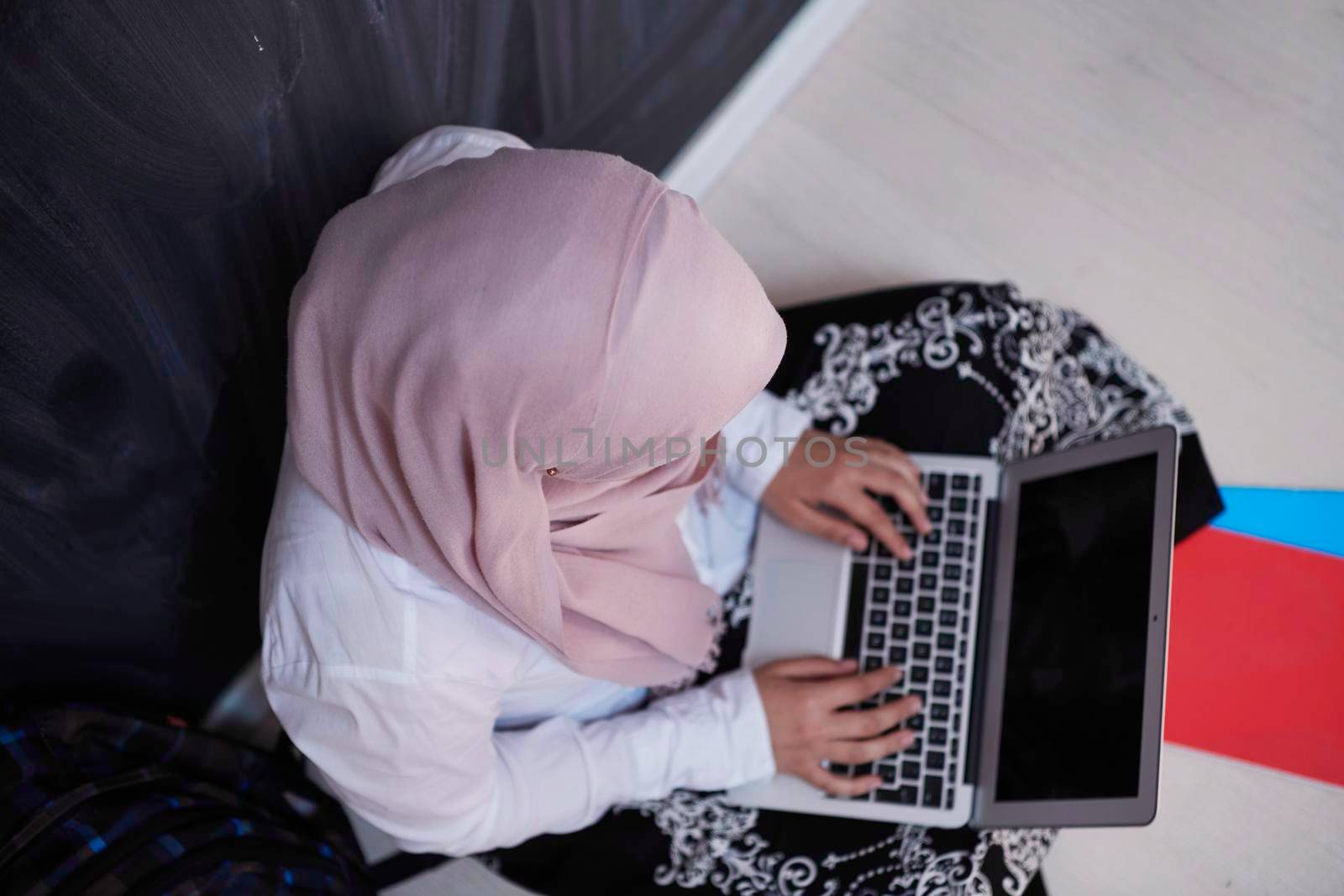 arab female student working on laptop from home  top view