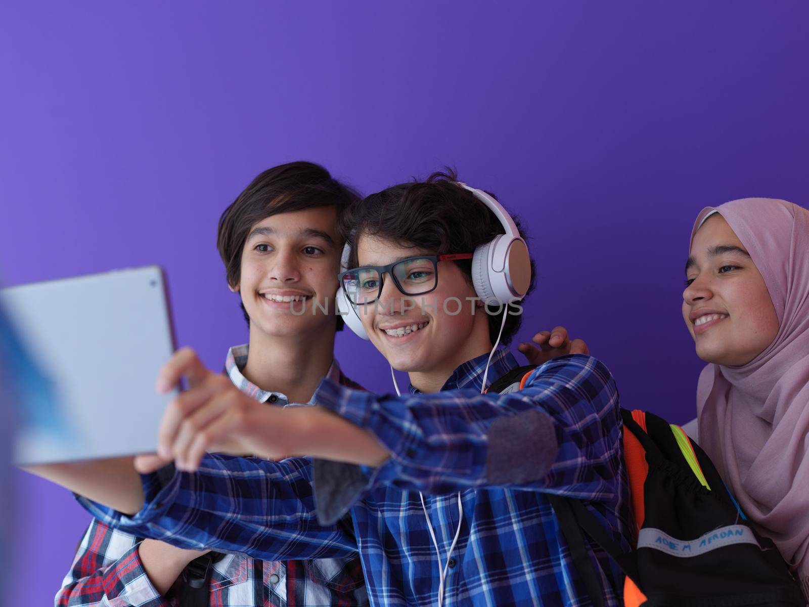 Arabic teenagers as team, students group working together on project using  laptop and tablet computer  online classroom  elearning education concept purple background