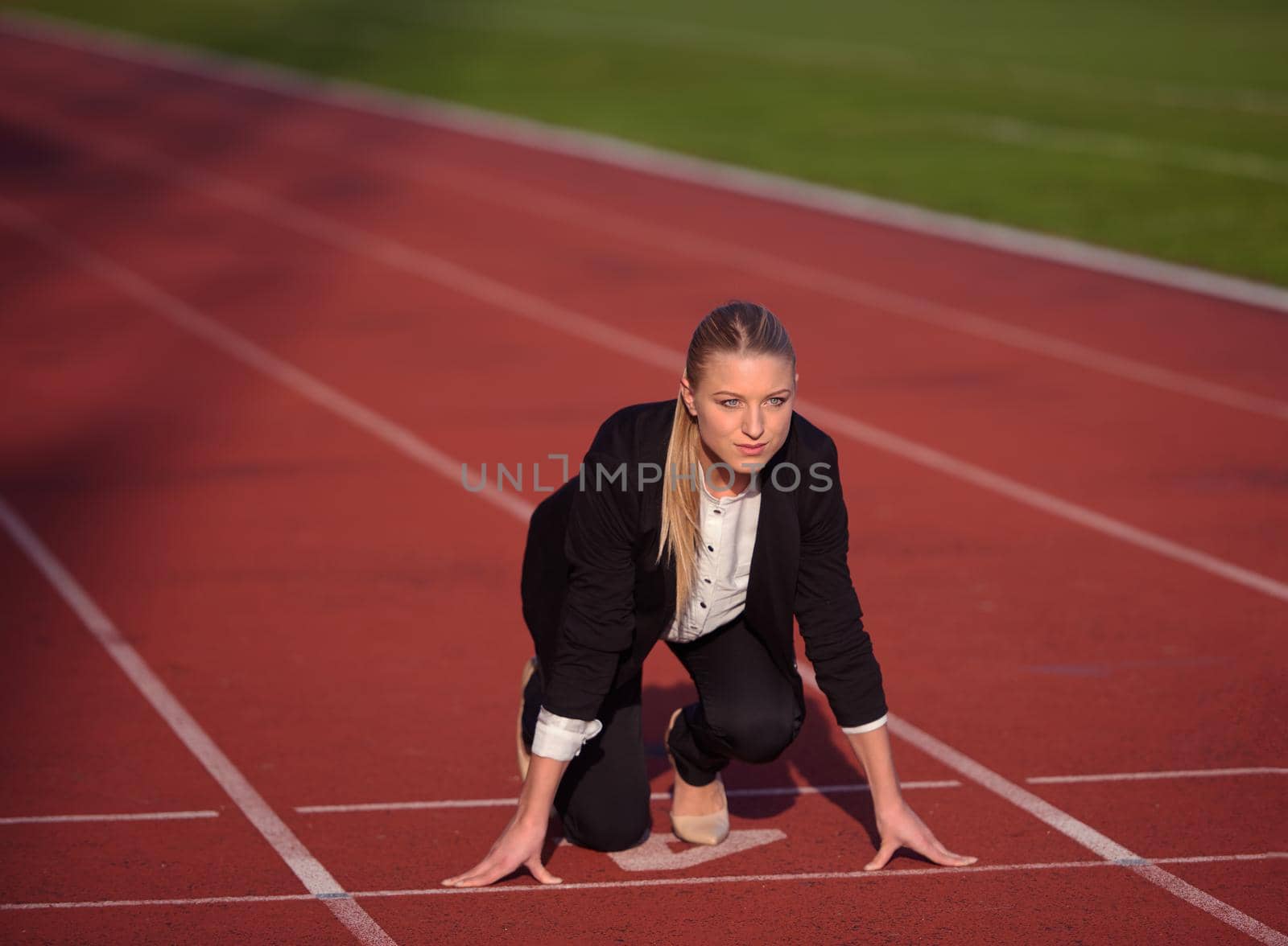 business woman in start position ready to run and sprint on athletics racing track