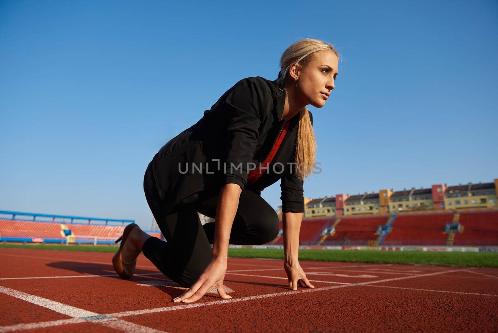 business woman in start position ready to run and sprint on athletics racing track