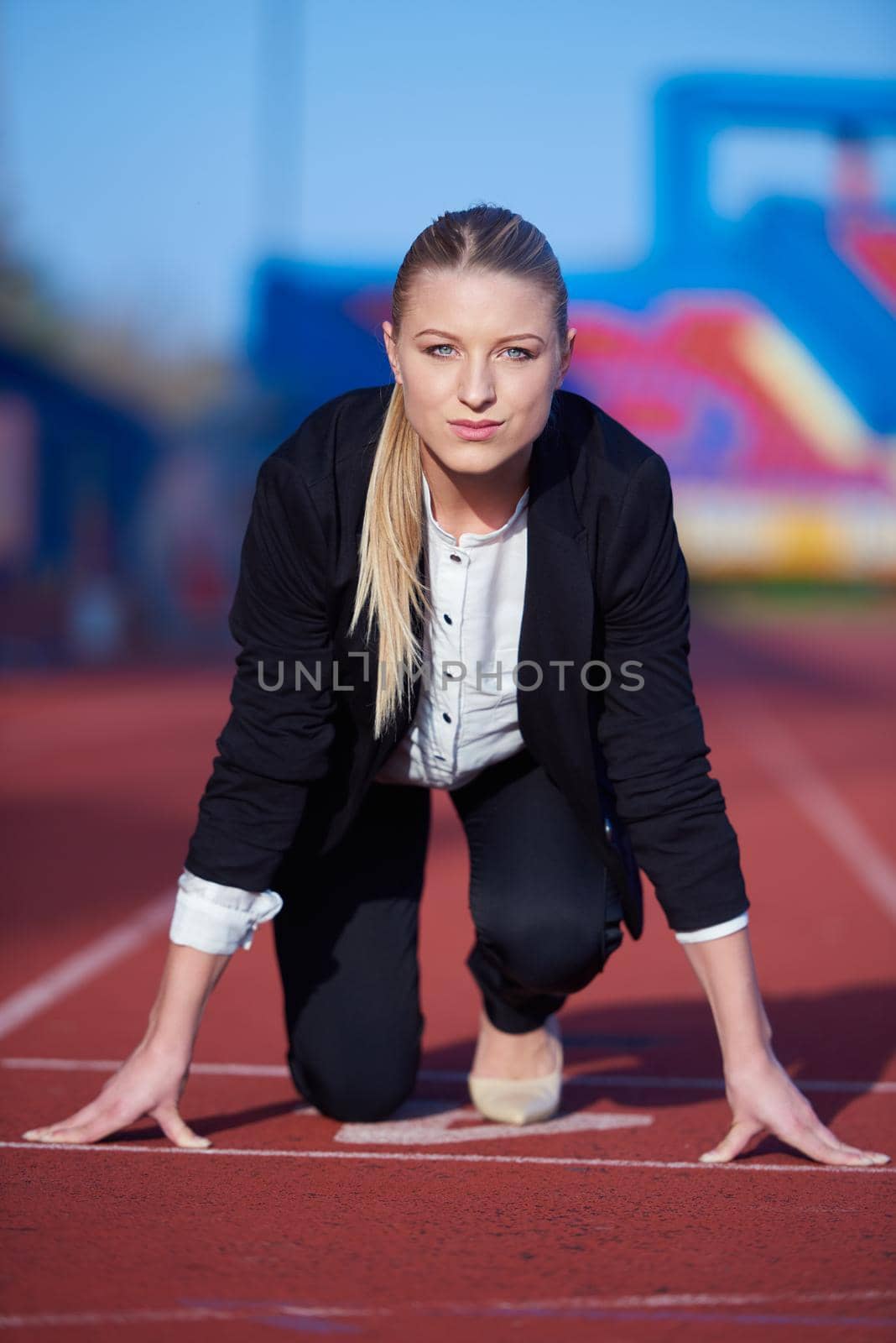 business woman in start position ready to run and sprint on athletics racing track