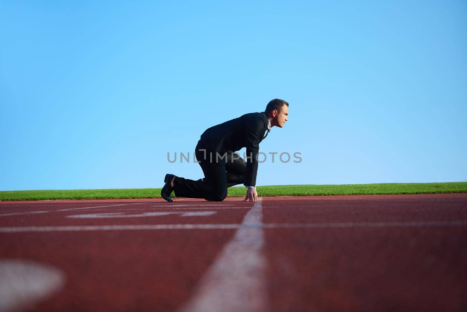 business man in start position ready to run and sprint on athletics racing track