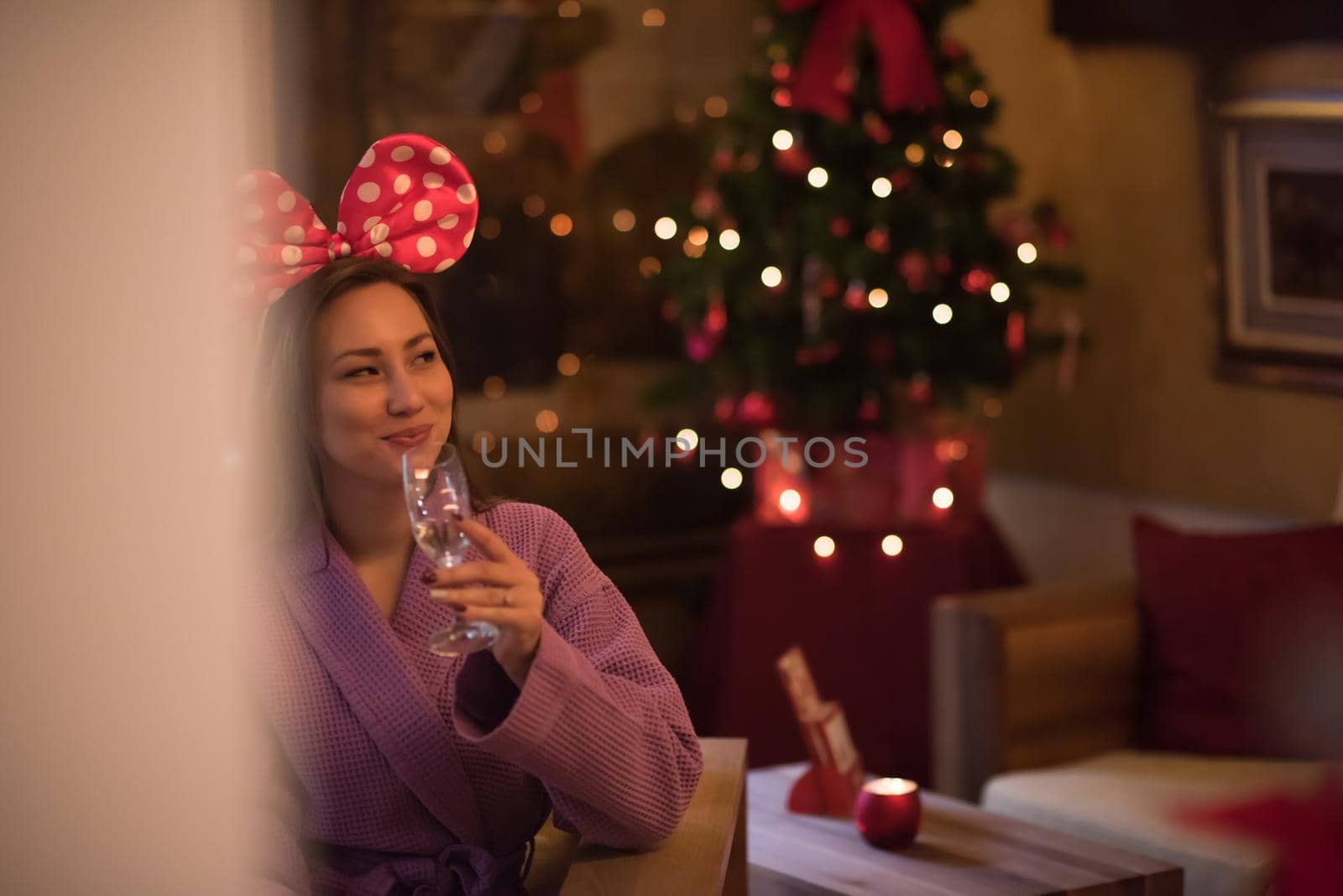 people, and relaxation concept   beautiful young woman in bath robe drinking champagne at spa over holidays lights background