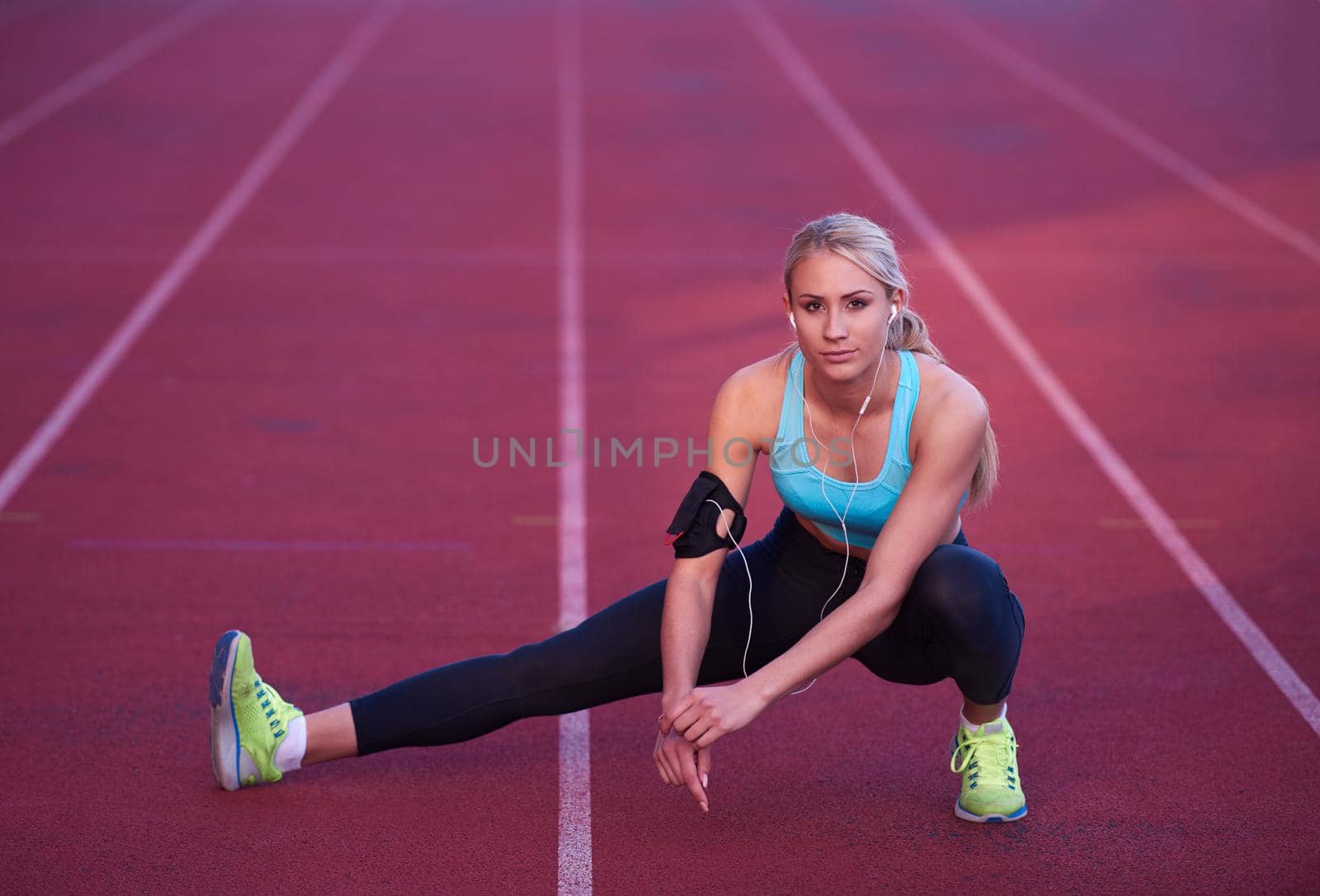 young runner sporty woman relaxing and stretching on athletic race track