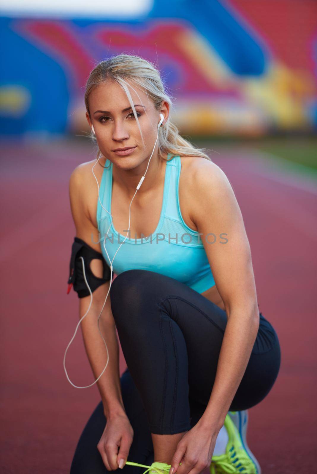 young runner sporty woman relaxing and stretching on athletic race track