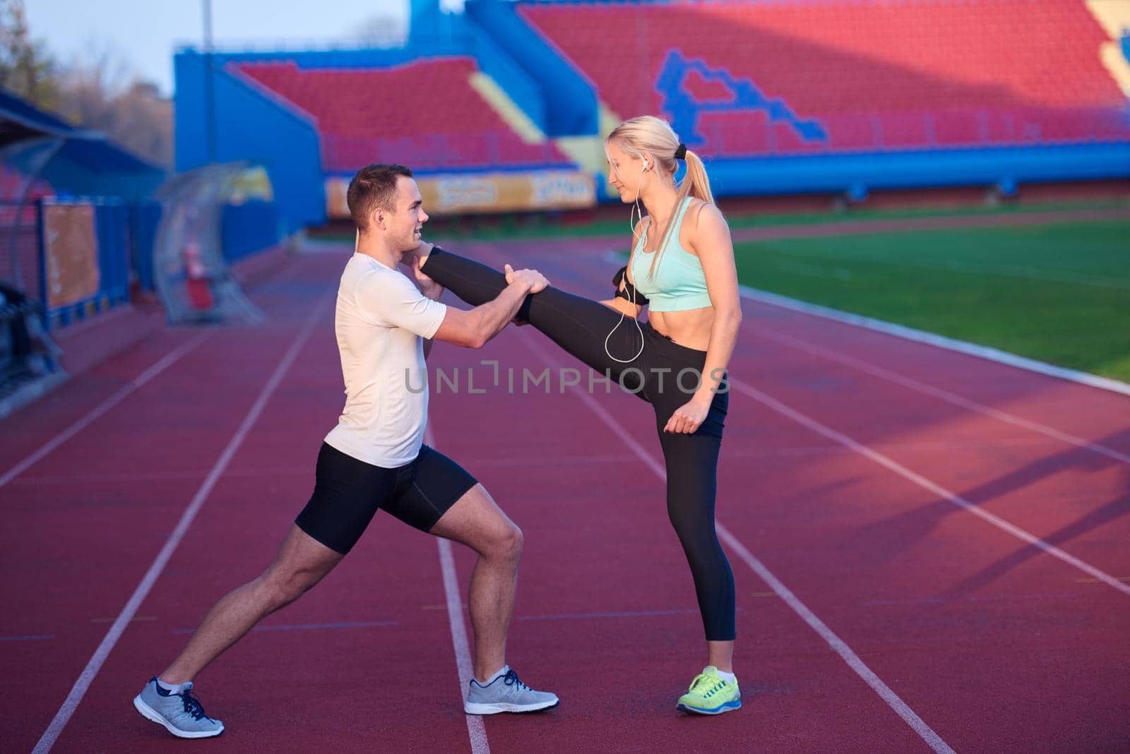 young runner sporty woman relaxing and stretching on athletic race track