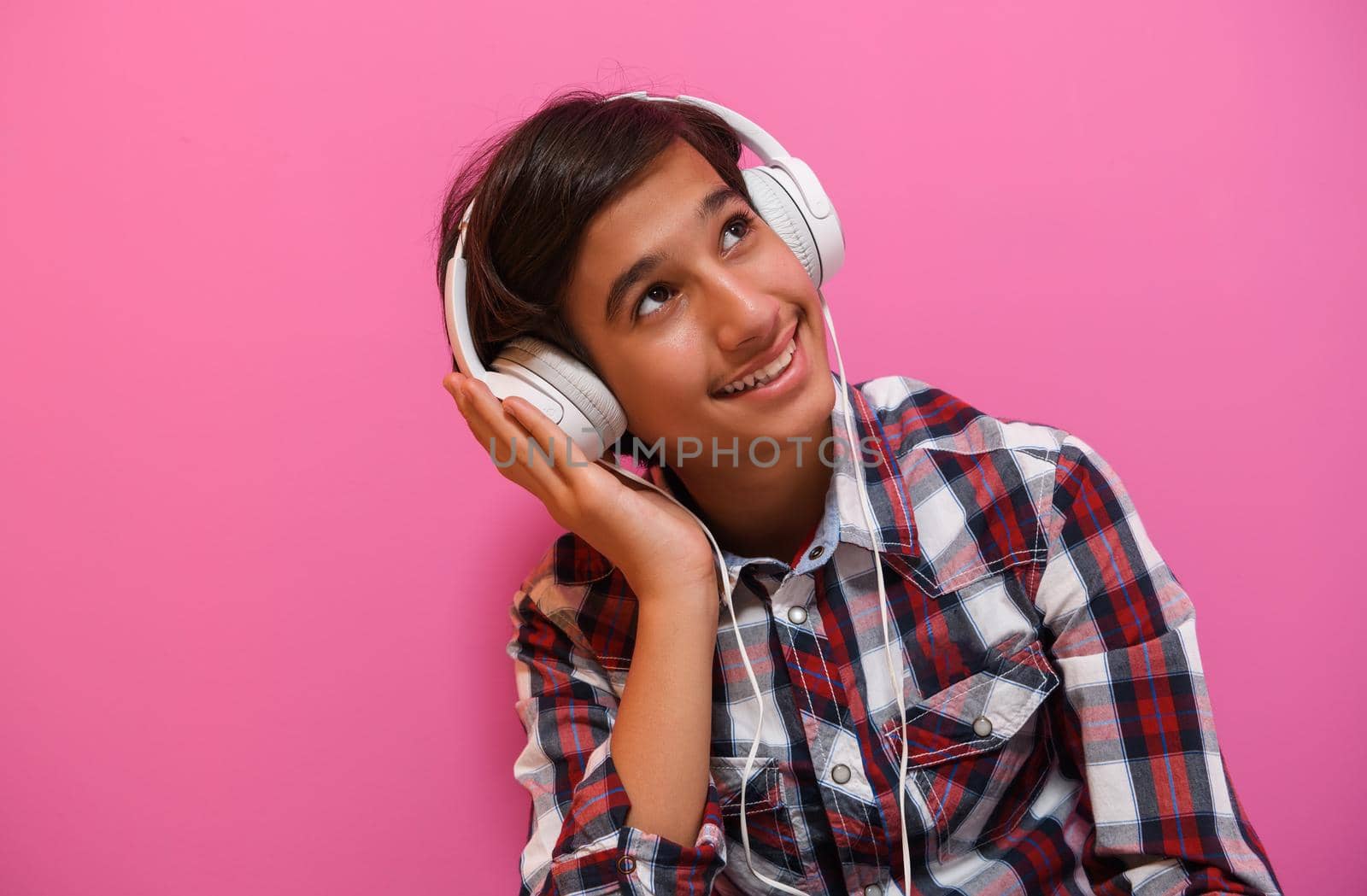 Arabic Teenage Boy Wearing Headphones And Listening To Music pink background by dotshock