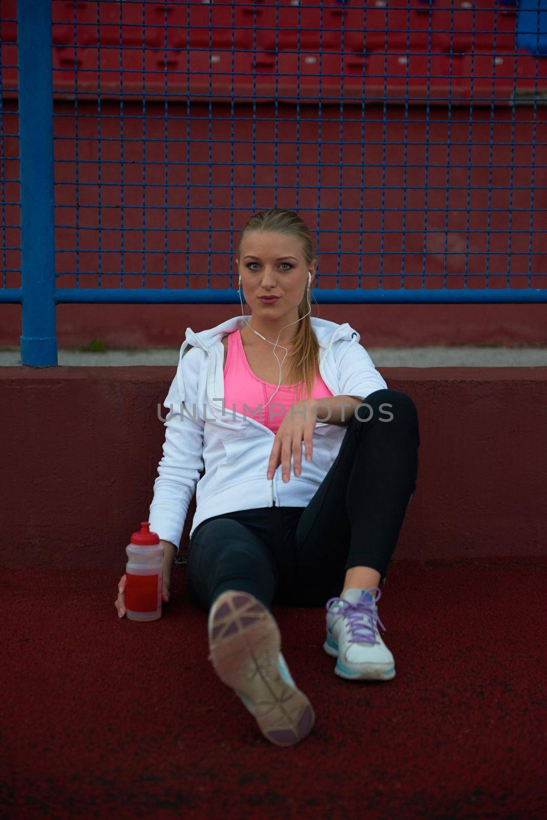 young runner sporty woman relaxing and stretching on athletic race track