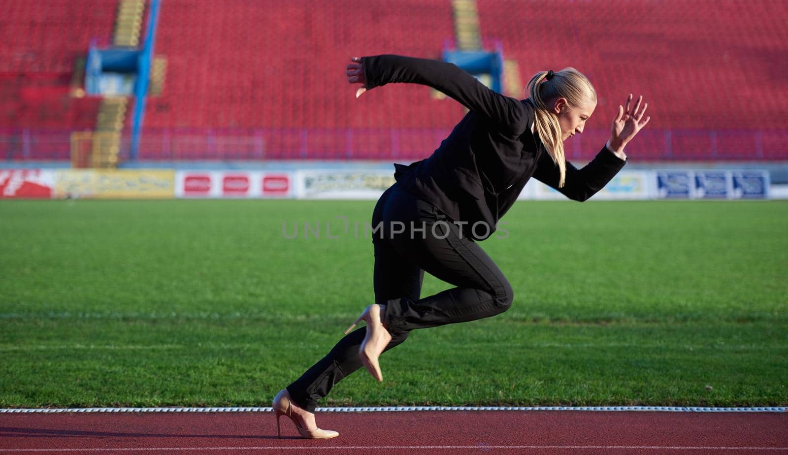 business woman in start position ready to run and sprint on athletics racing track