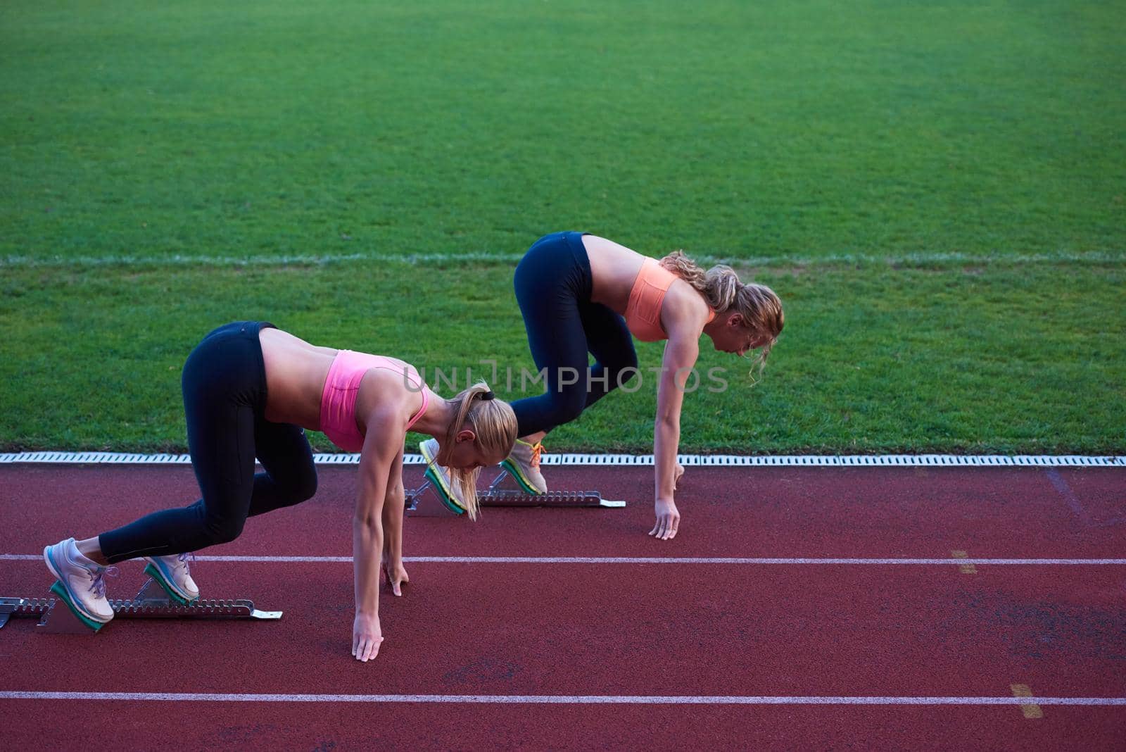 athlete woman group  running on athletics race track on soccer stadium and representing competition and leadership concept in sport