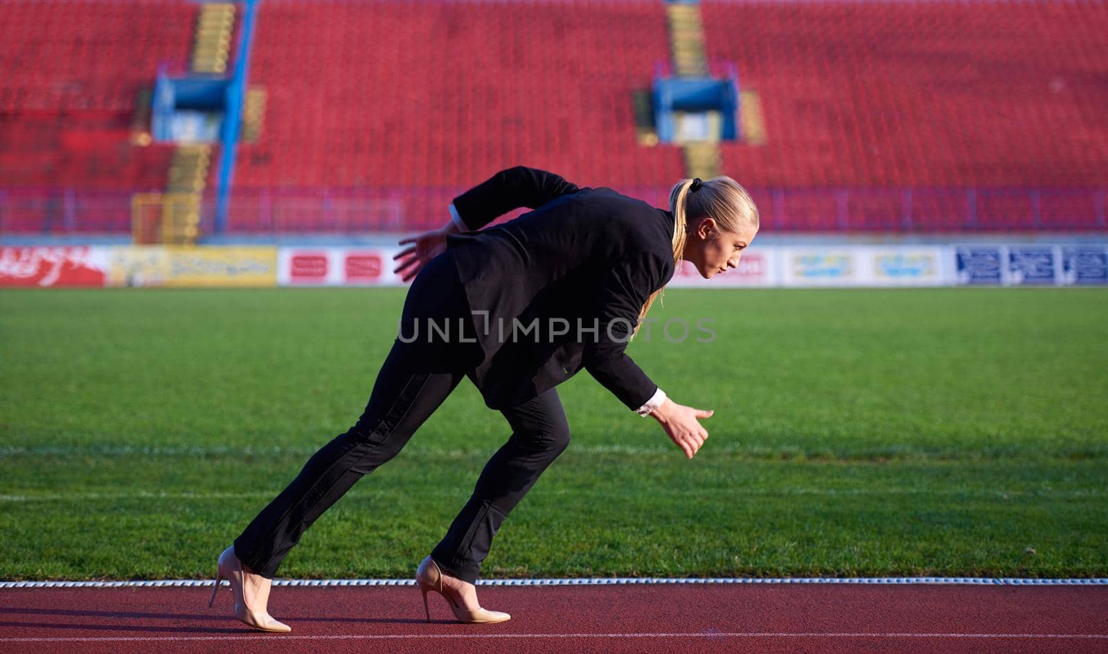 business woman in start position ready to run and sprint on athletics racing track