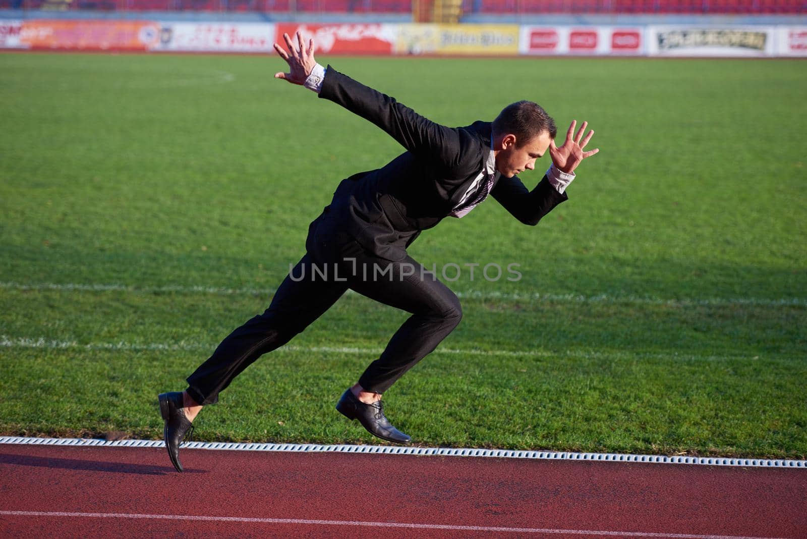 business man in start position ready to run and sprint on athletics racing track