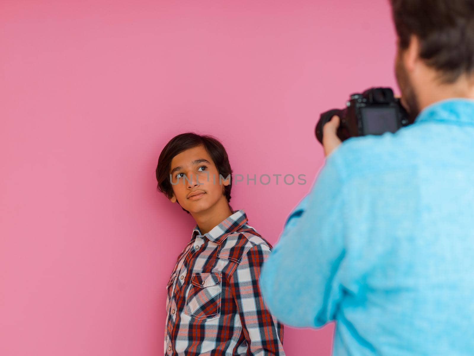 A photo of a father and son taking family photos in the house in front of a purple wall. Selective focus. High quality photo
