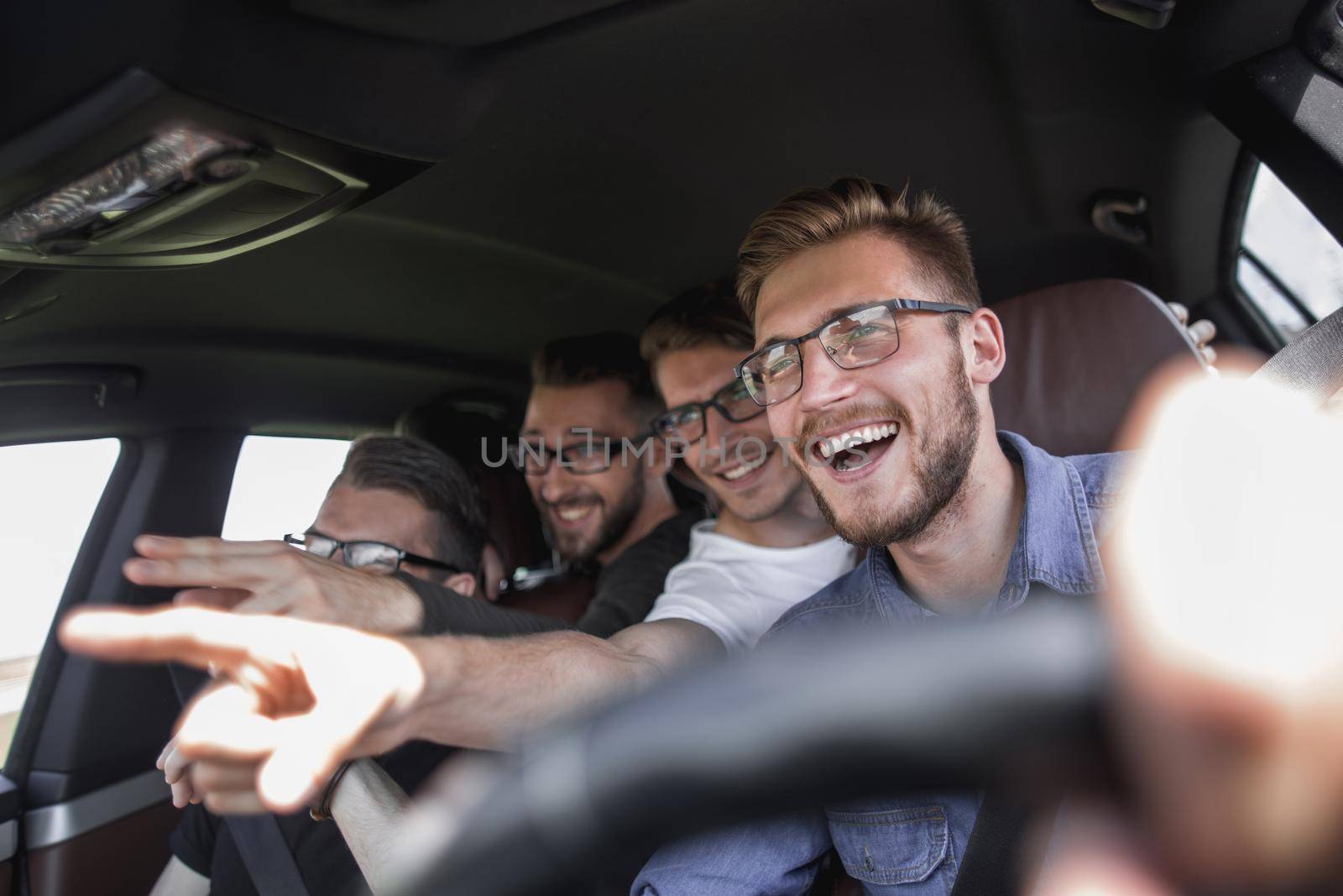 Group of happy friends on a car. Focus on the man by asdf