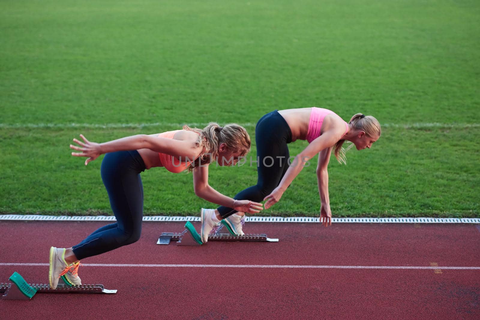 athlete woman group  running on athletics race track on soccer stadium and representing competition and leadership concept in sport