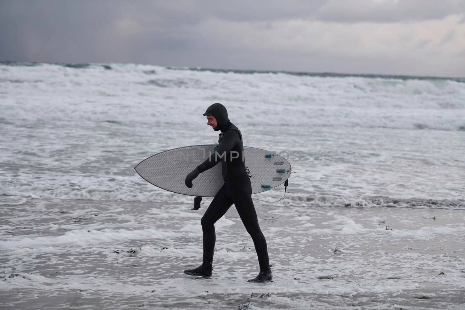 Arctic surfer going by beach after surfing by dotshock