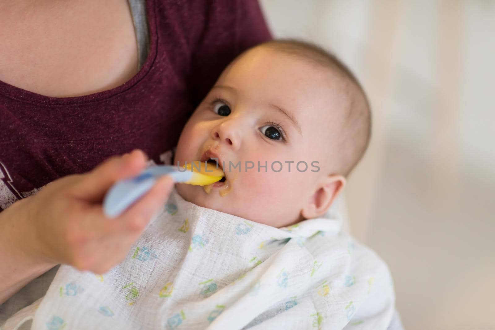 family, food, child, eating and parenthood concept   mother with spoon feeding little baby boy at home