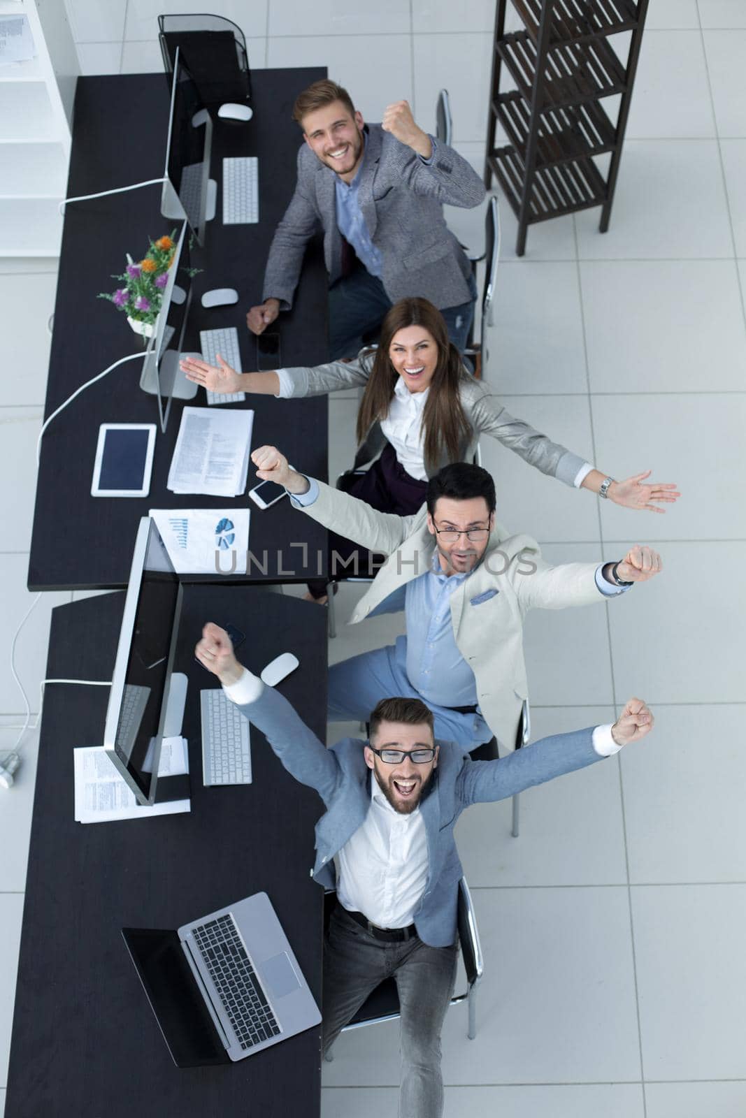 top view.happy business team sitting at the Desk.the concept of success in work