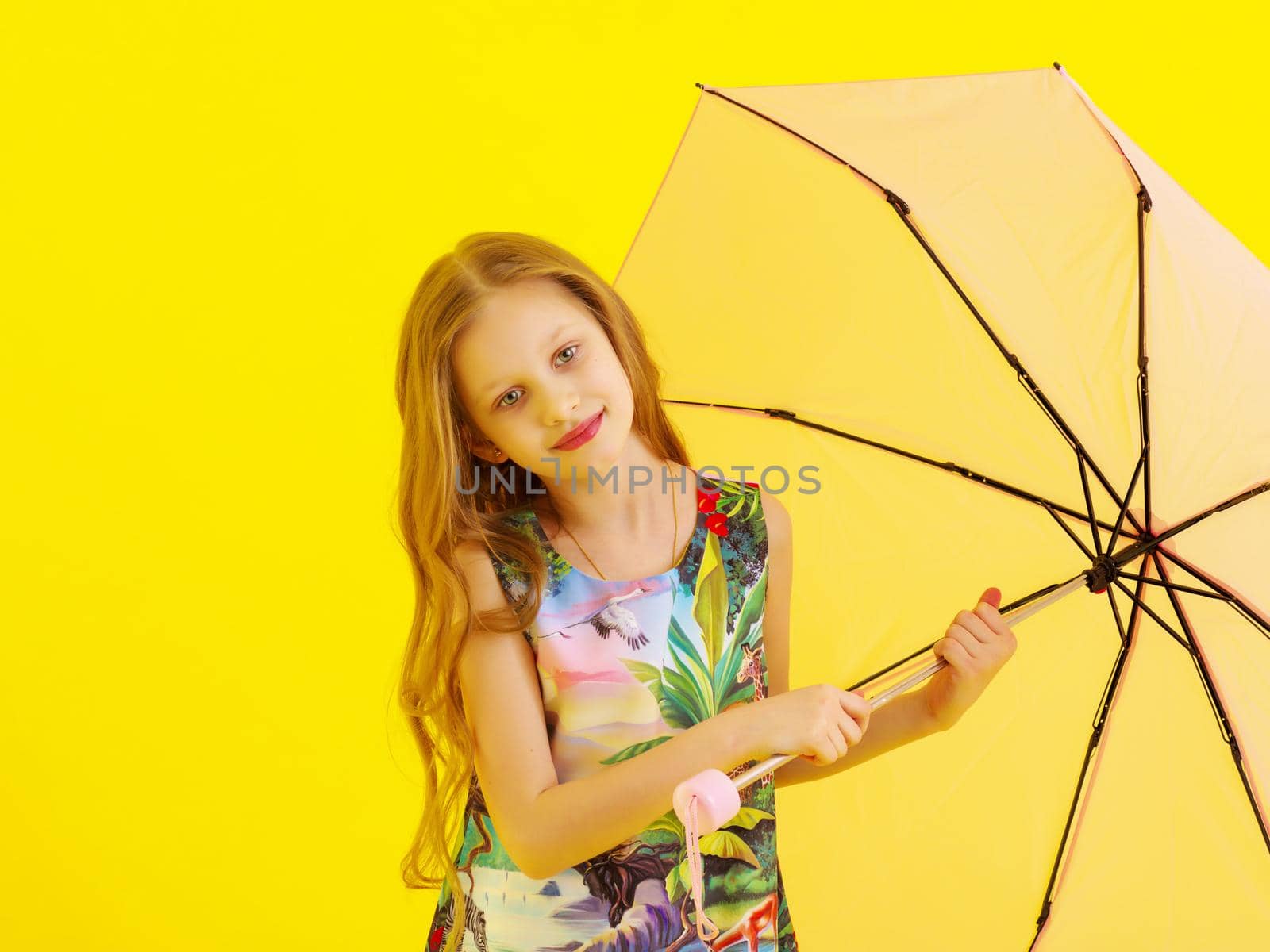 A nice little girl hid under an umbrella. The concept of a happy childhood, outdoor recreation, protection from bad weather. Isolated.