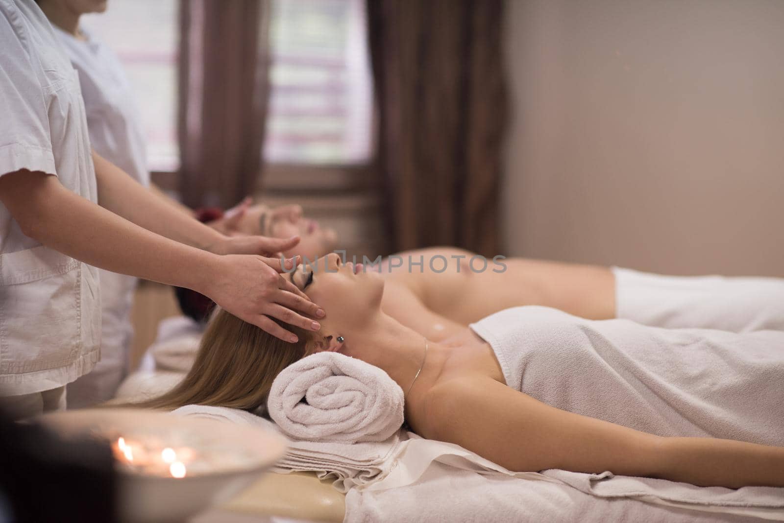 happy young beautiful couple enjoying head massage at the spa