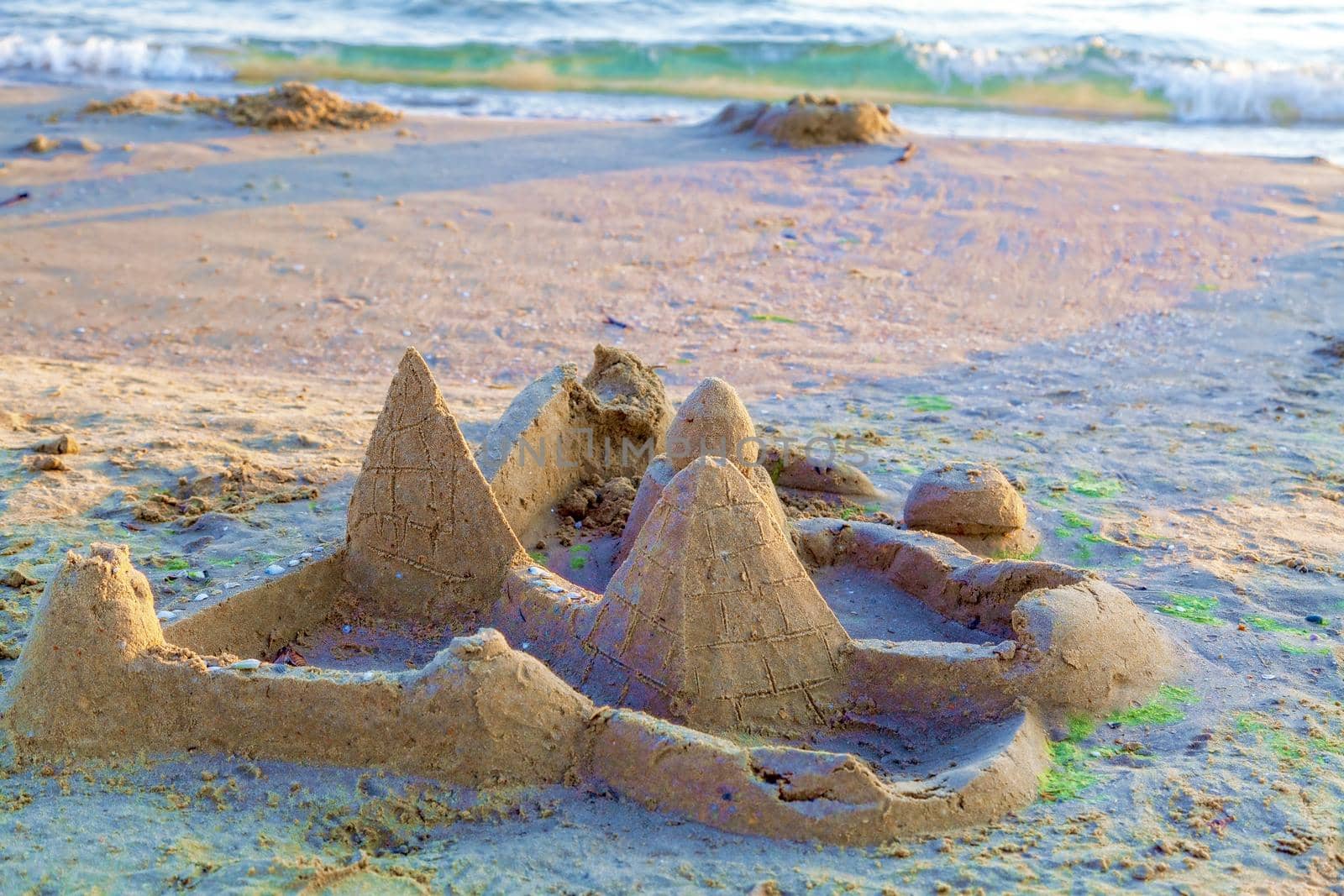 Beautiful sand castle illuminated by the morning sun on the beach of the tropical sea. The concept of a family vacation at sea.