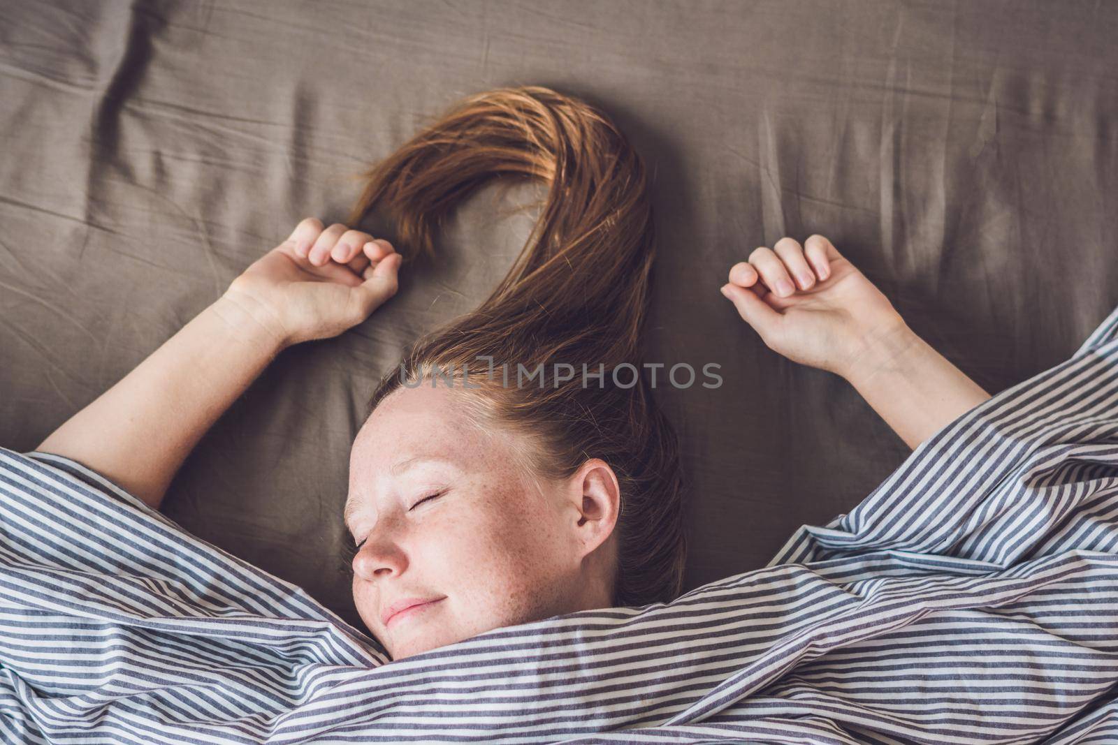 Beautiful young woman lying down in bed and sleeping, top view. Do not get enough sleep concept by galitskaya