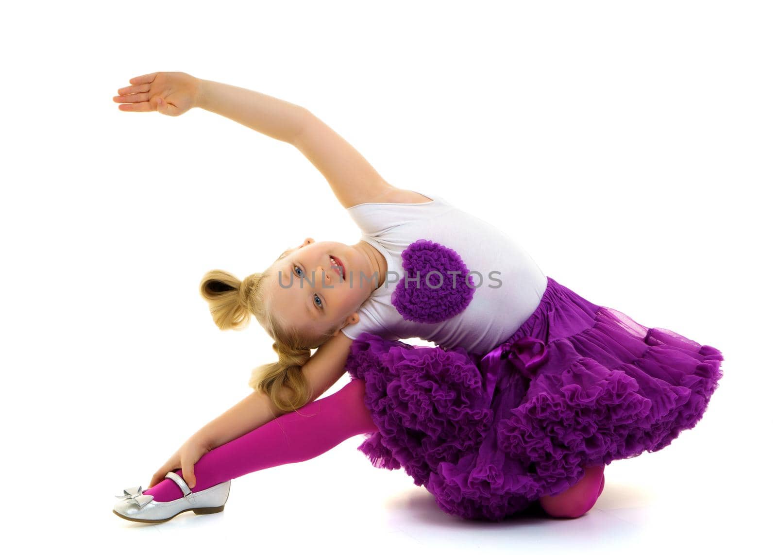 A sweet little gymnast girl performs an acrobatic element on the floor. The concept of sport, healthy lifestyle. Isolated on white background.