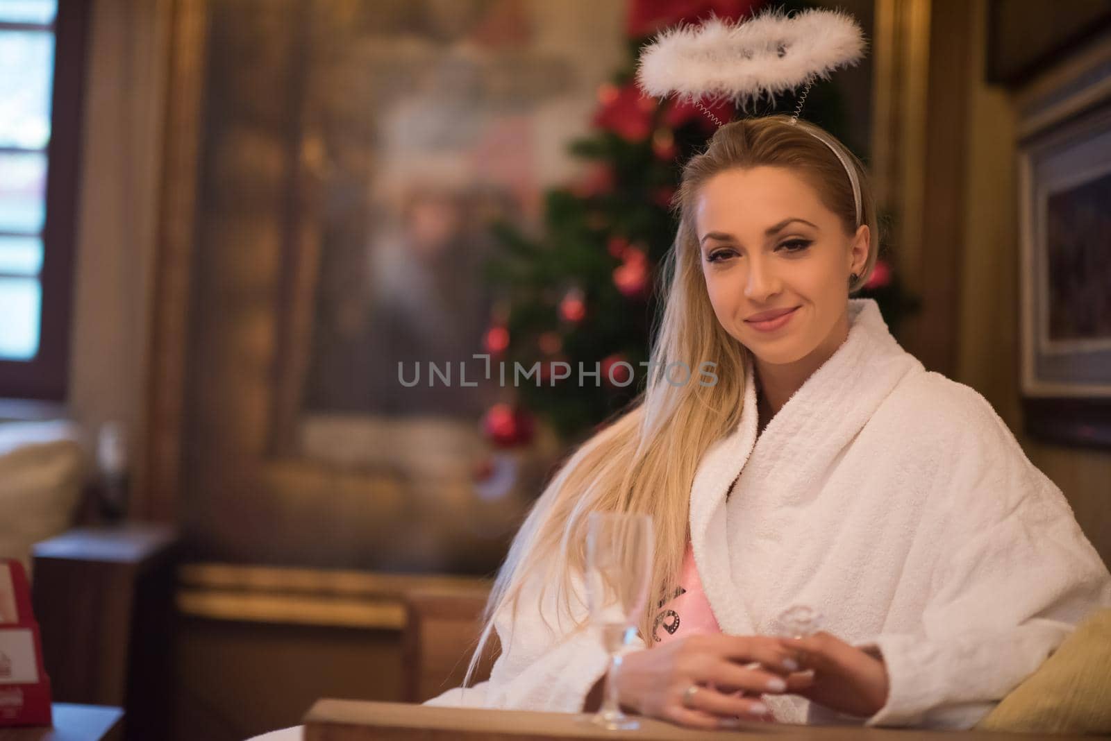 people, and relaxation concept   beautiful young woman in bath robe drinking champagne at spa over holidays lights background