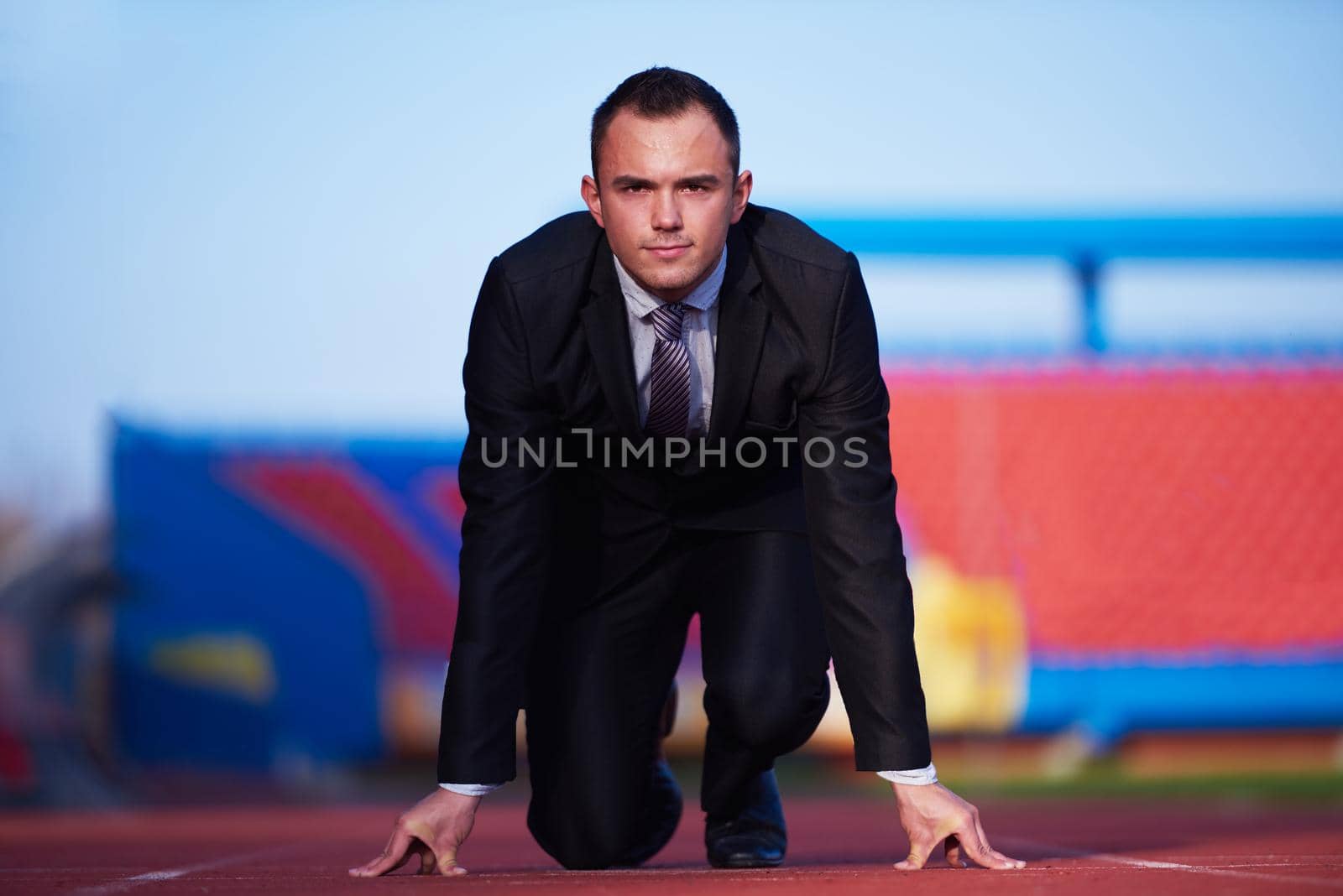 business man in start position ready to run and sprint on athletics racing track