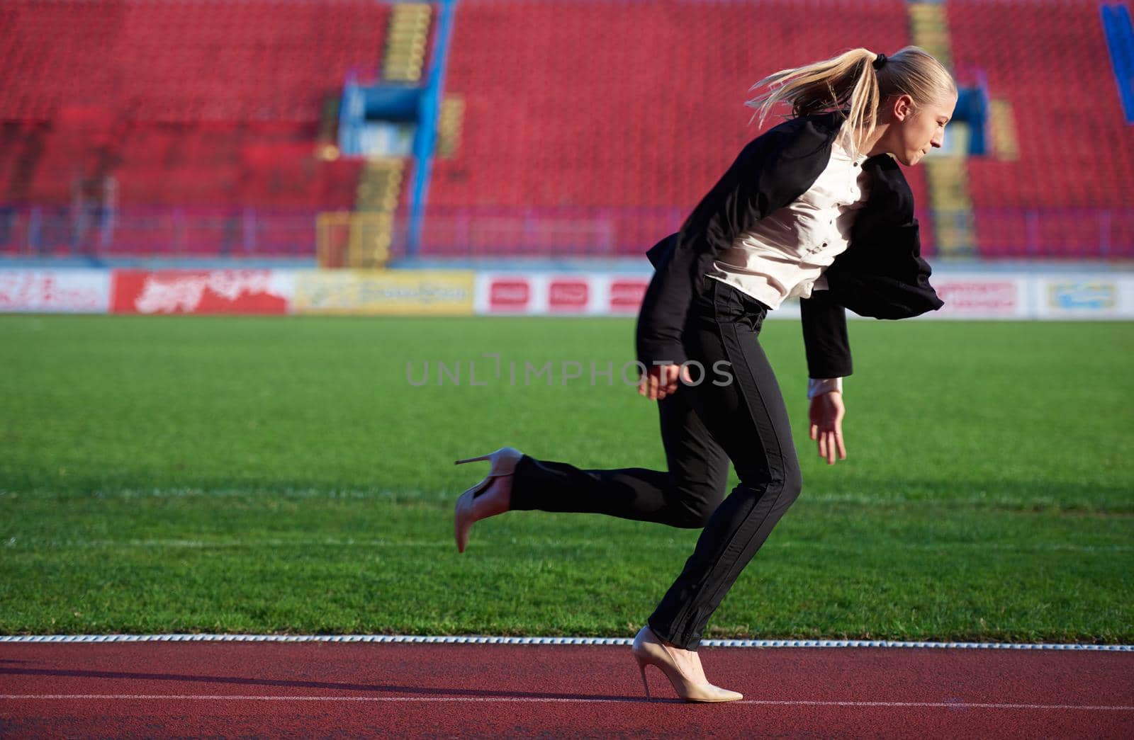 business woman in start position ready to run and sprint on athletics racing track