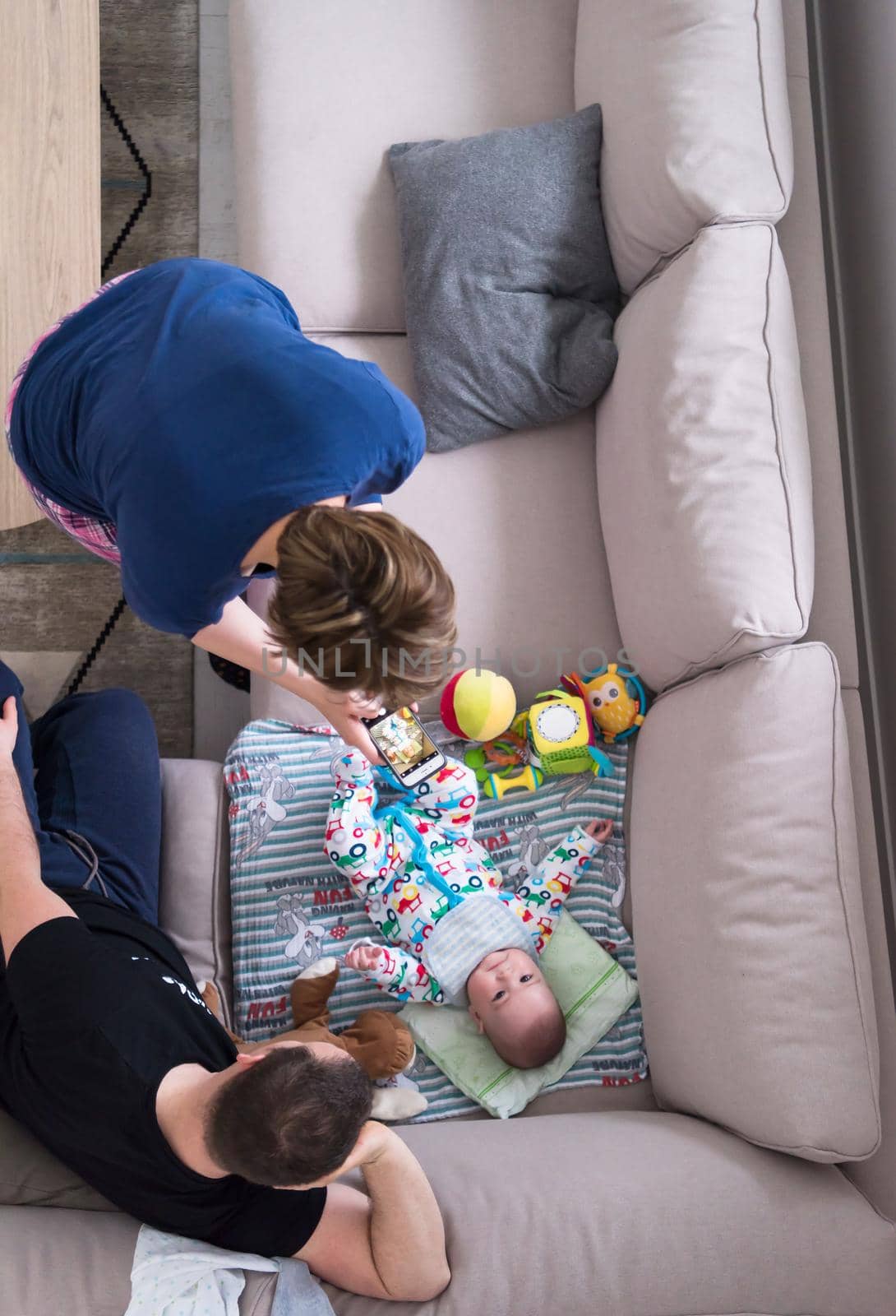 top view of happy mother and father taking picture of baby by dotshock