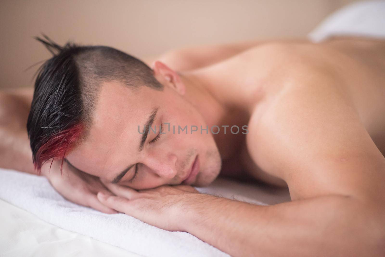 attractive handsome man resting in a spa massage center, lying on table relaxing closed eyes  concept of men beauty health care