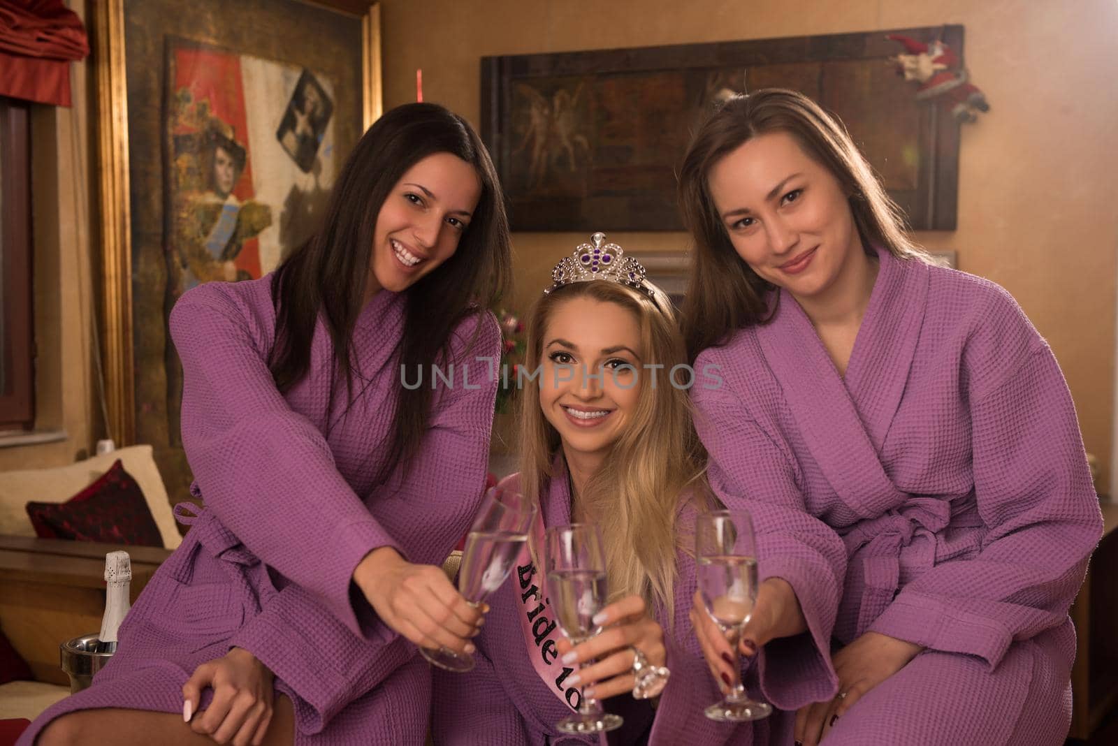 three young beautiful happy girls have a bachelor party at a luxury spa with champagne