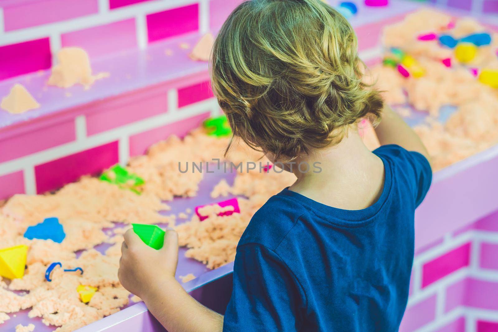 Boy playing with kinetic sand in preschool. The development of fine motor concept. Creativity Game concept by galitskaya