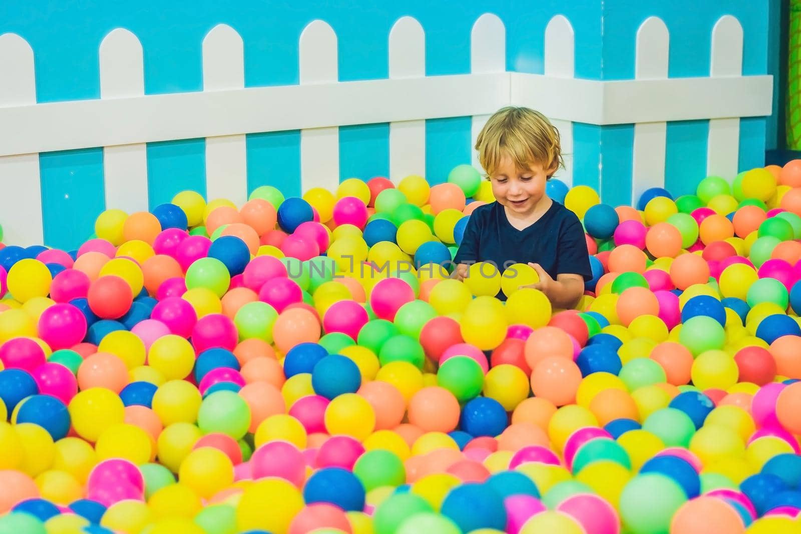 Happy little kid boy playing at colorful plastic balls playground high view. Funny child having fun indoors by galitskaya