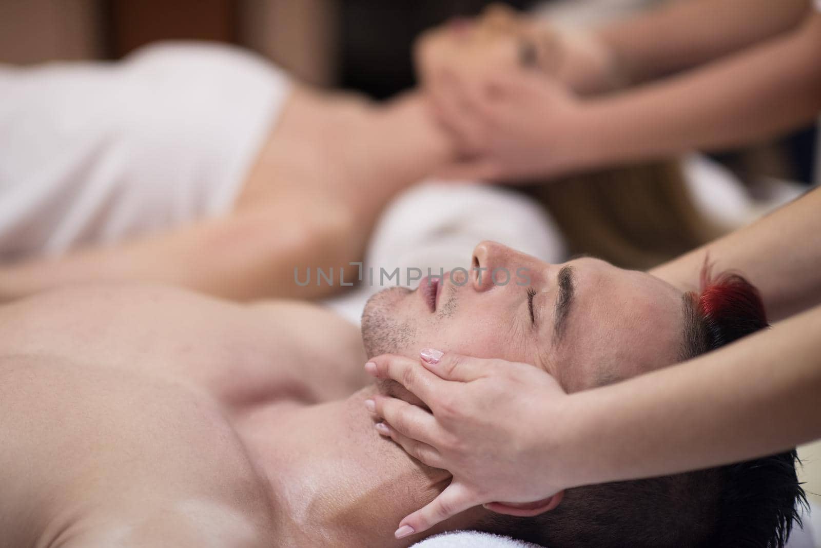 couple enjoying head massage at the spa by dotshock