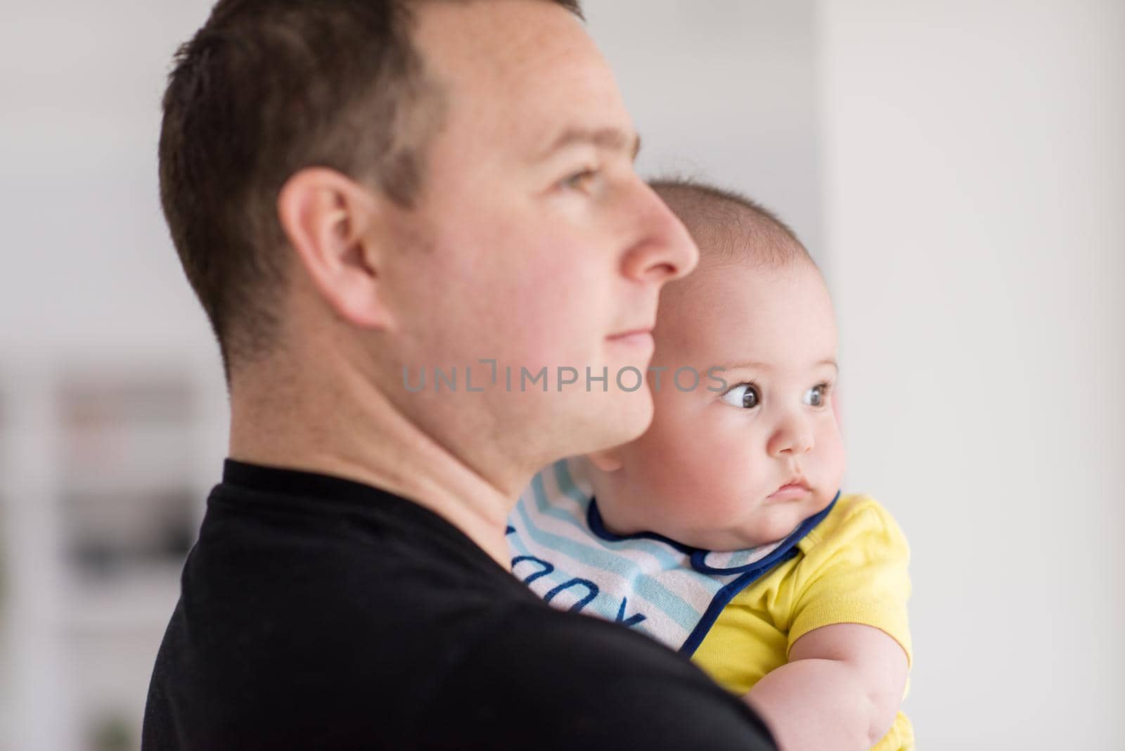 young father holding baby near the window at home by dotshock