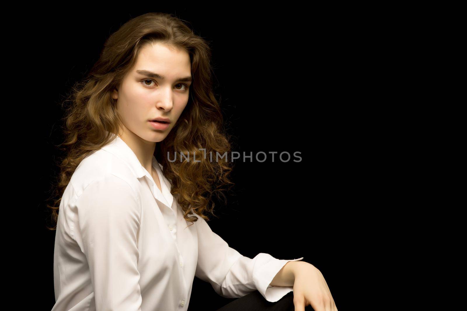 Beautiful teenage girl, studio photo. The concept of fashion and style. On a black background.