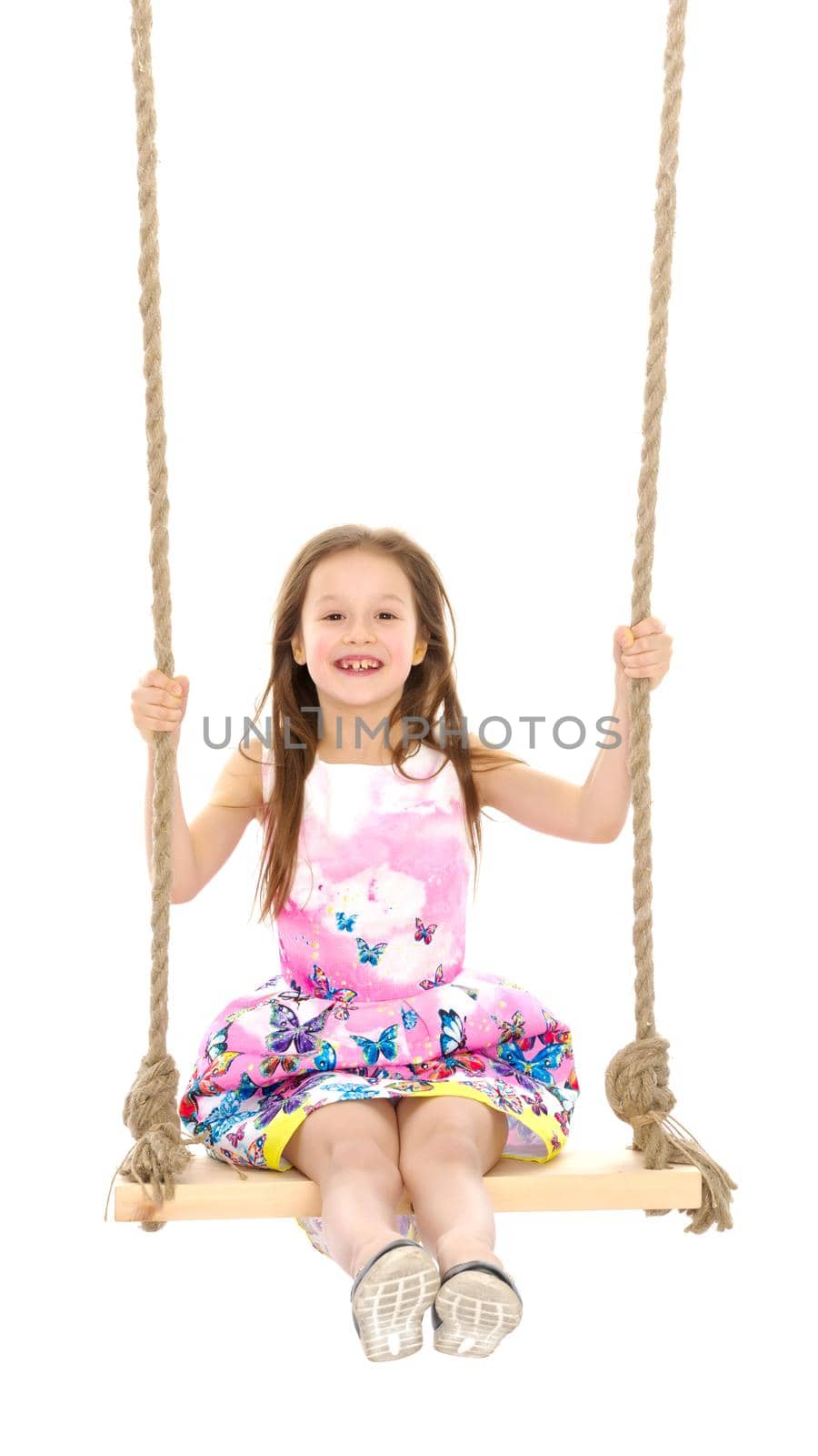 Adorable little girl swinging on a swing. She is happy to have fun and show how she can do it. The concept of summer recreation and harmonious development of the child. Isolated on white