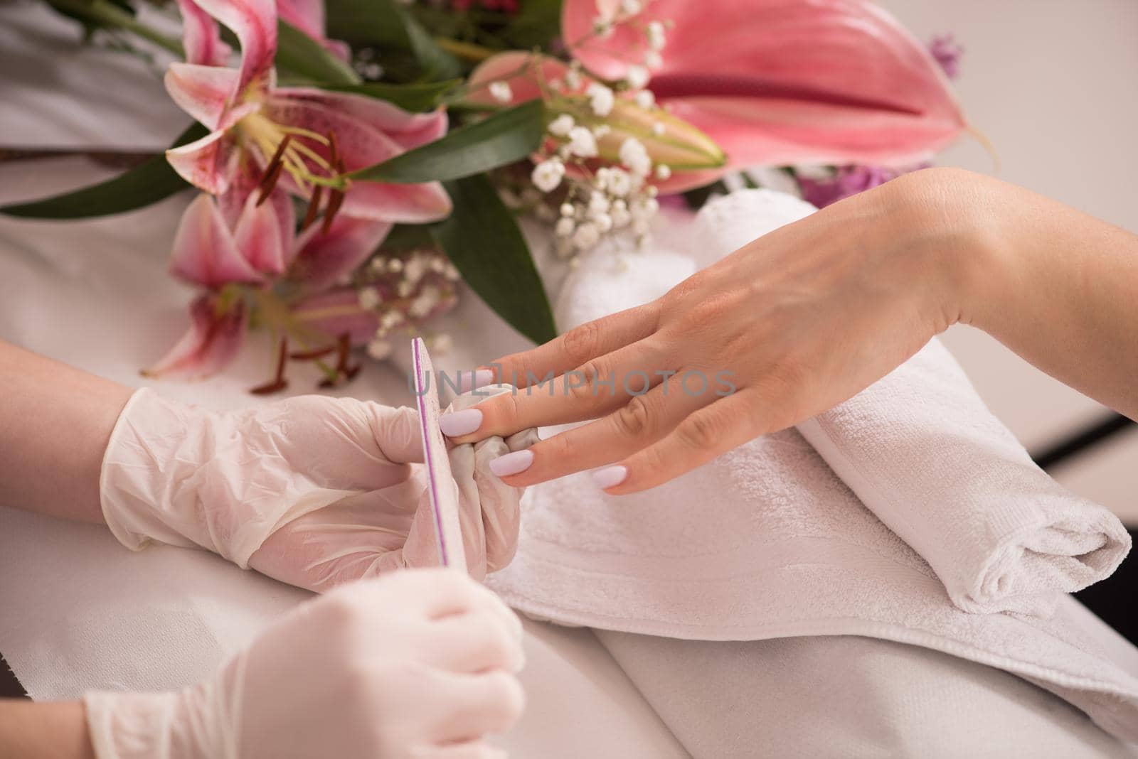 Woman hands receiving a manicure in beauty salon. Nail filing. Close up, selective focus.