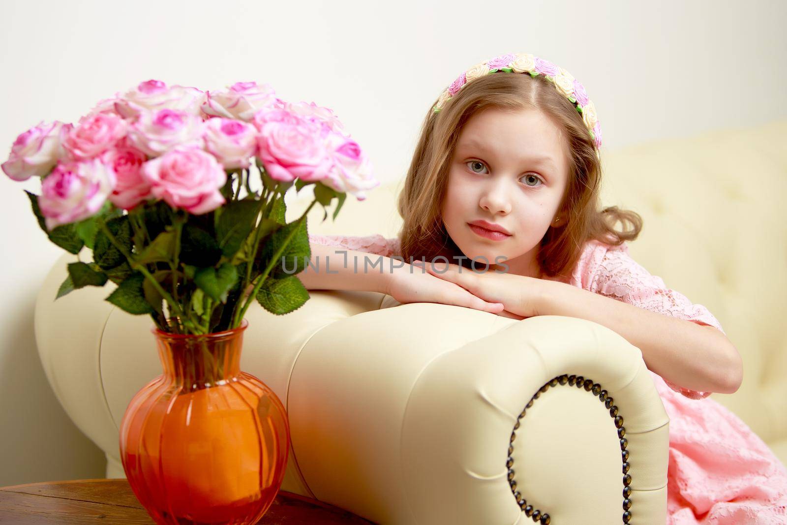 Happy little girl with a bouquet of flowers sitting on the couch. The concept of a holiday, a spring mood.