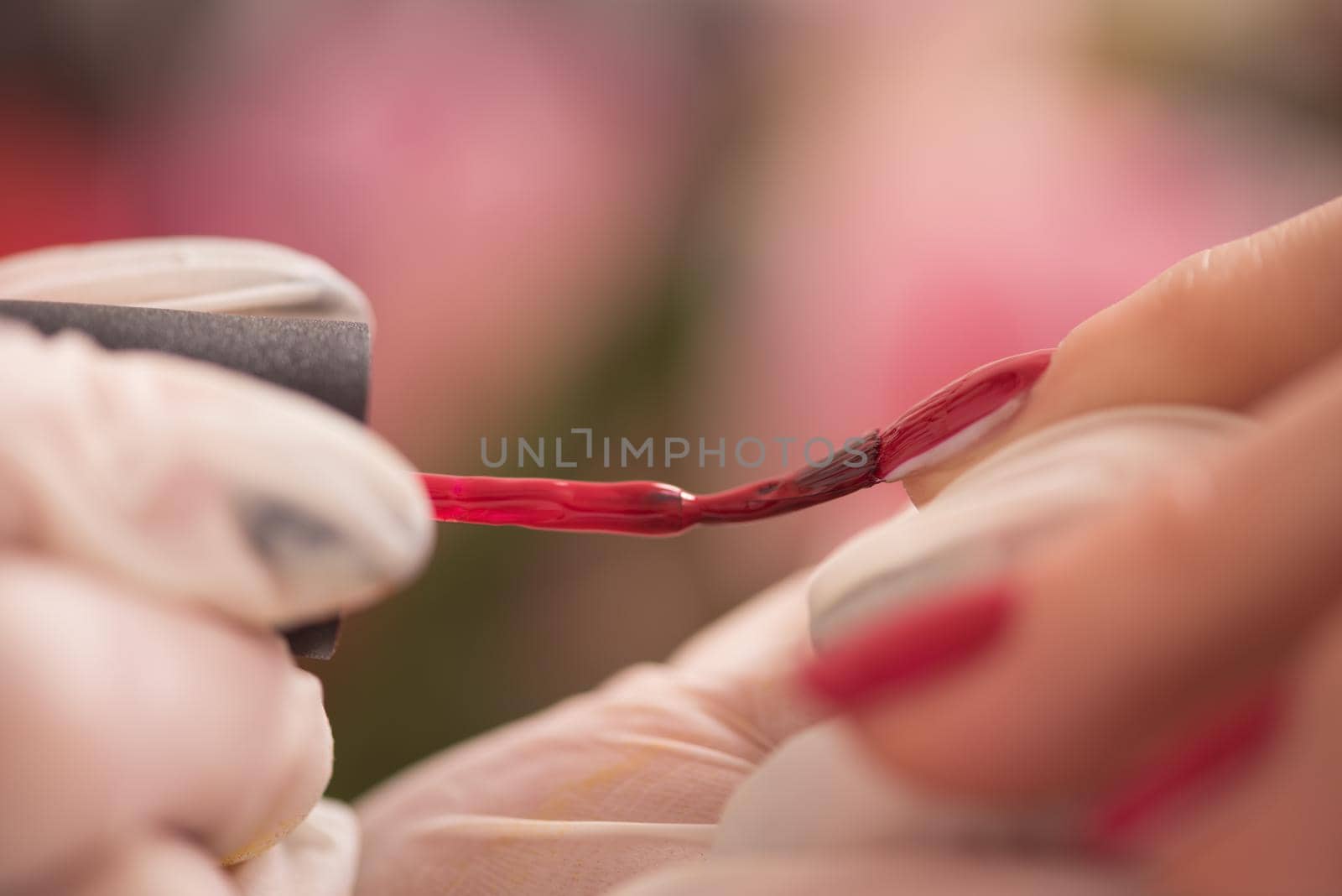 Woman hands receiving a manicure in beauty salon. Nail filing. Close up, selective focus.