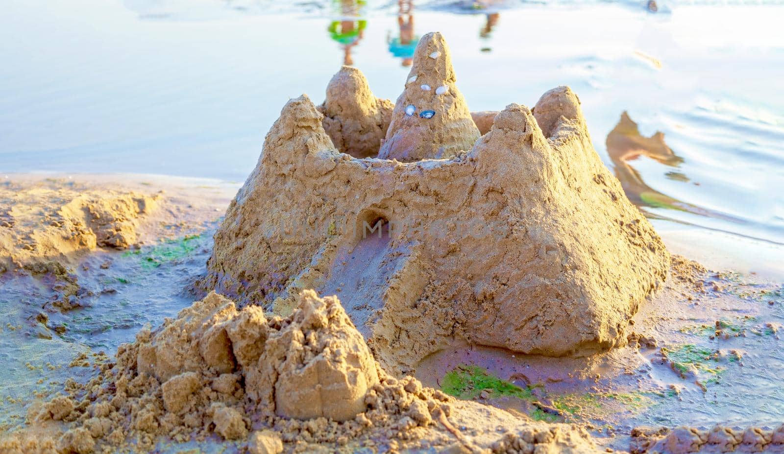 Beautiful sand castle illuminated by the morning sun on the beach of the tropical sea. The concept of a family vacation at sea.