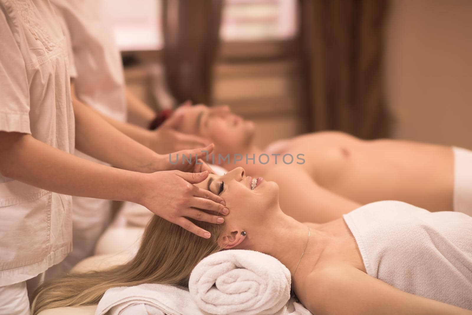 happy young beautiful couple enjoying head massage at the spa