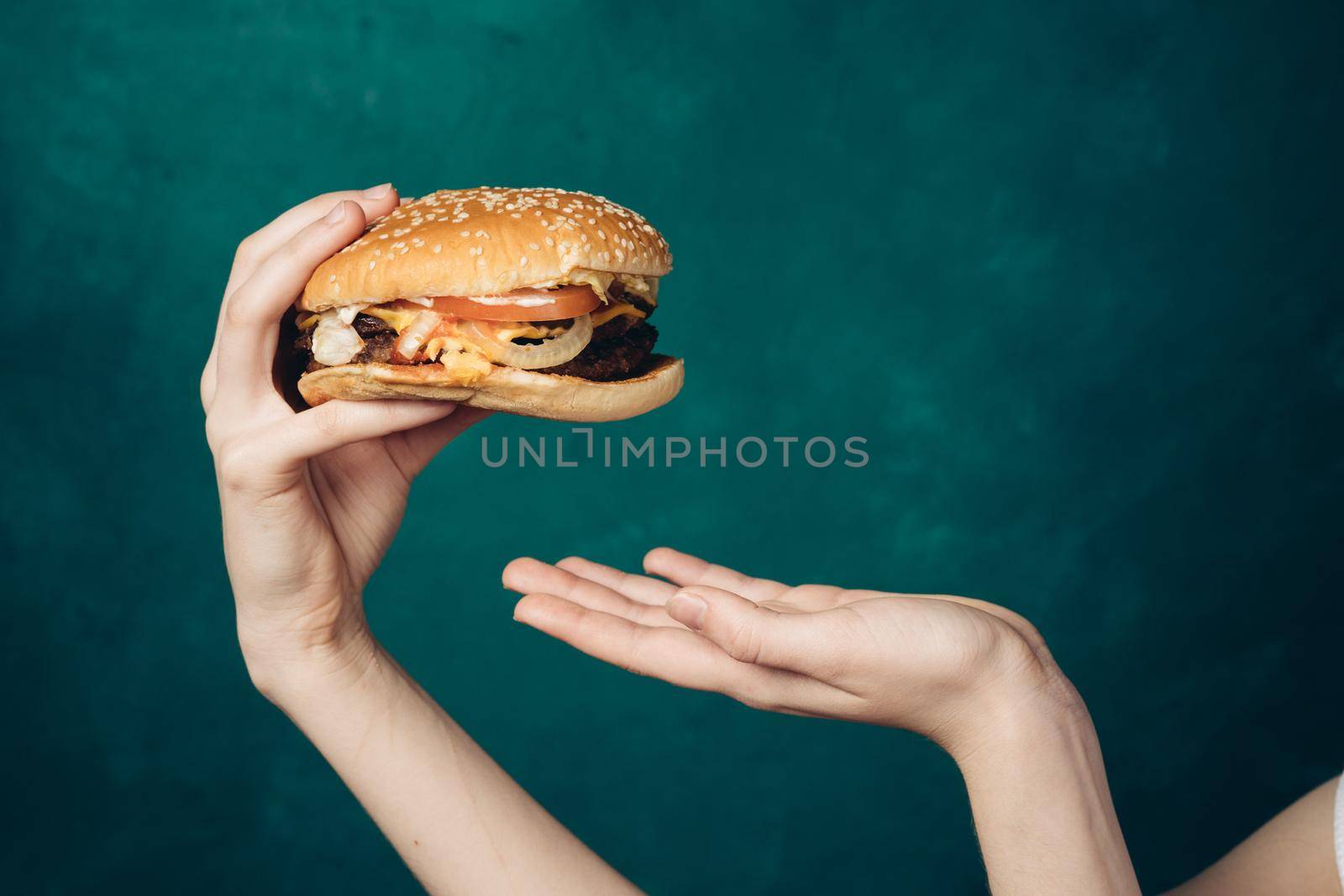 hamburger in hands close-up fast food green background by Vichizh