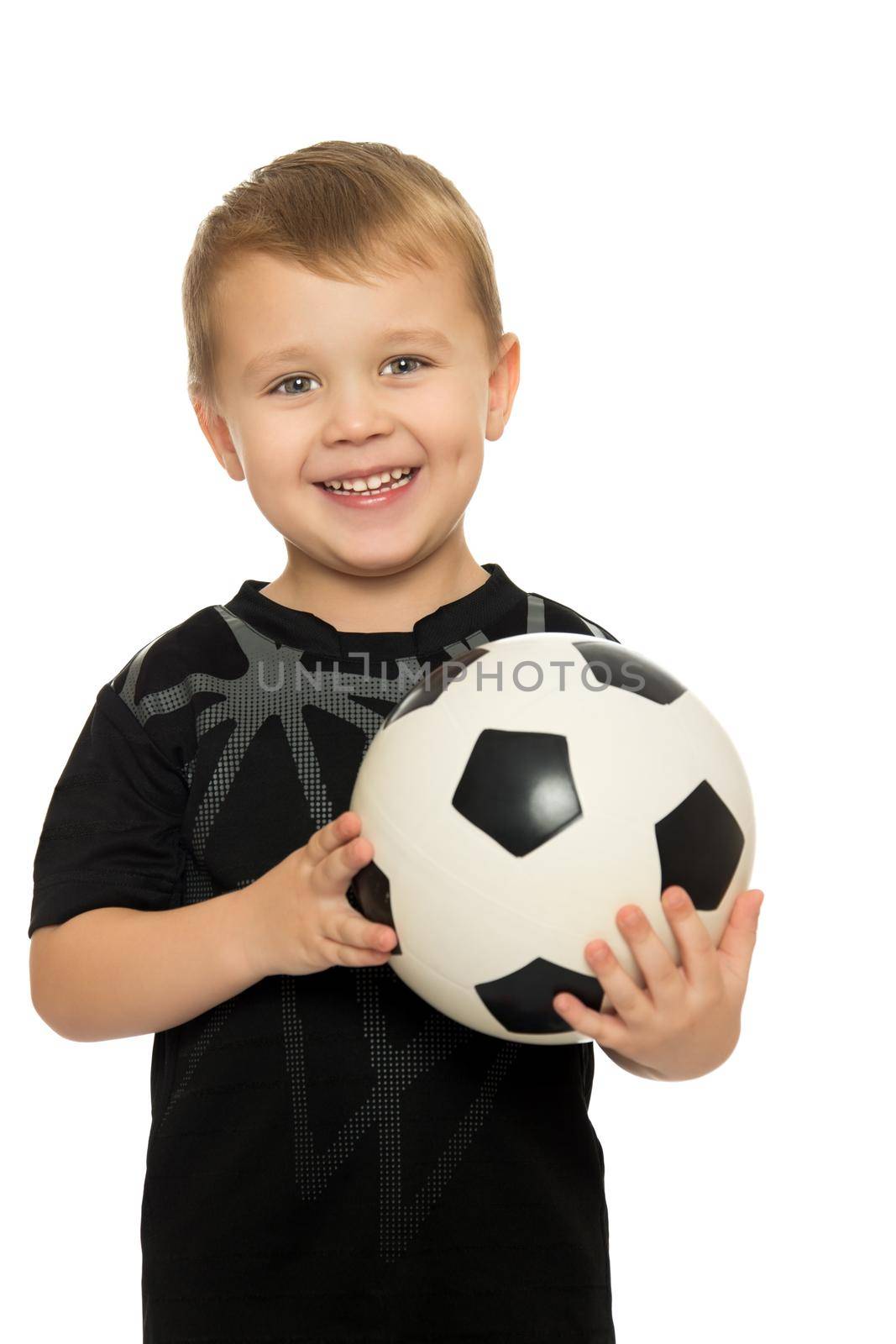 Portrait of a cheerful little boy football player in black uniform. The boy holds a hand soccer ball.Close-up - Isolated on white background