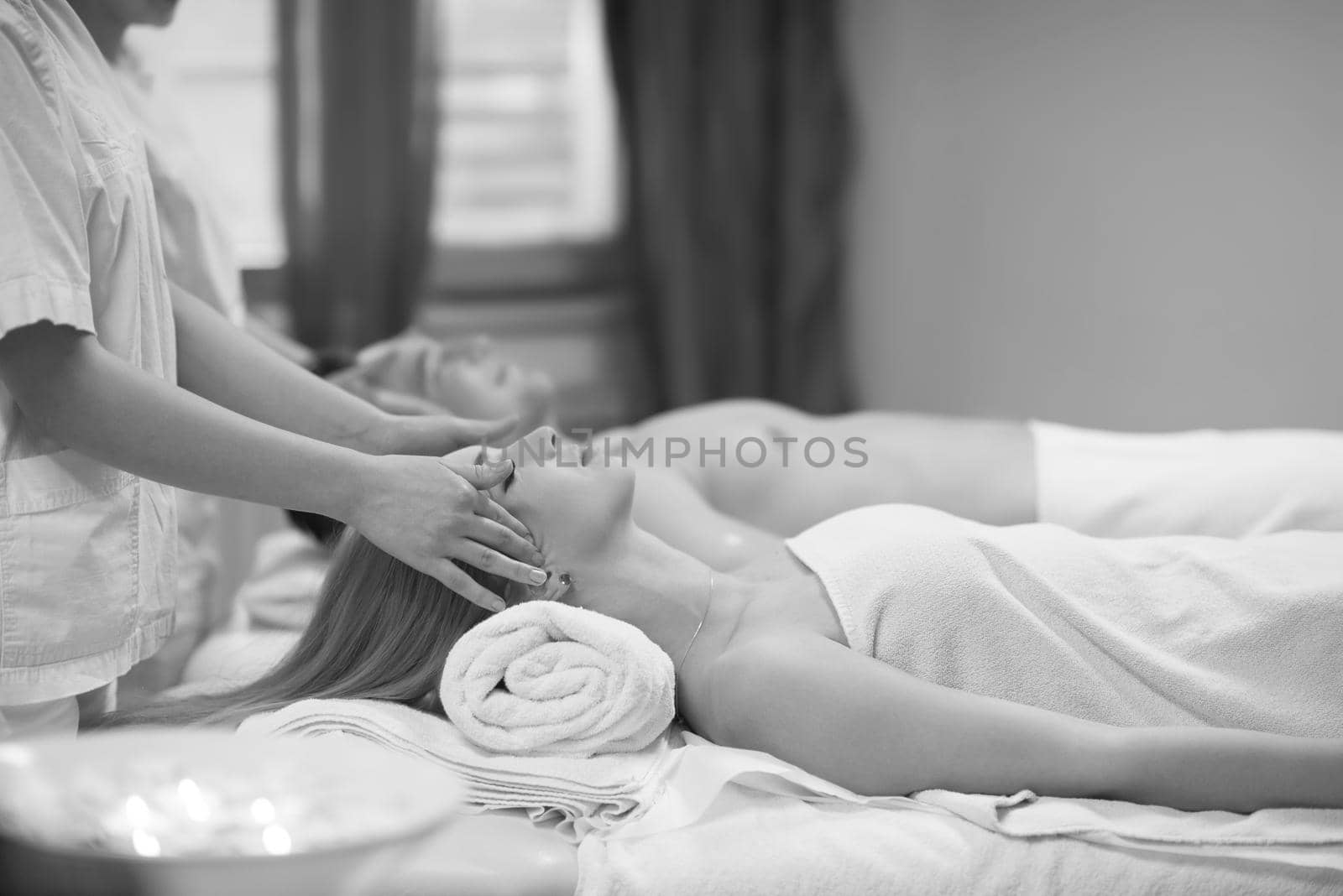 happy young beautiful couple enjoying head massage at the spa