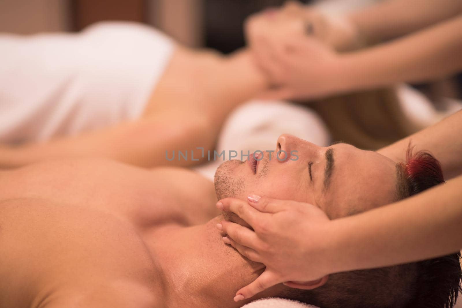 happy young beautiful couple enjoying head massage at the spa