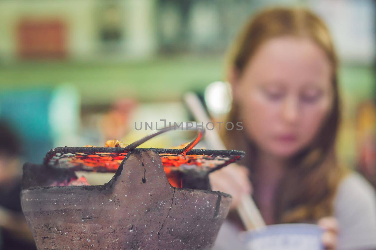 Girl frying meat on a small grill in a restaurant by galitskaya